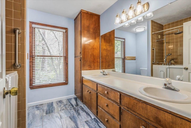 full bathroom featuring double vanity, toilet, an enclosed shower, a sink, and baseboards