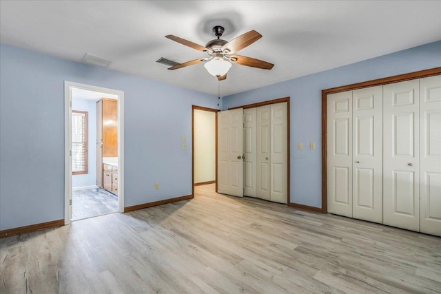 unfurnished bedroom with baseboards, two closets, and wood finished floors