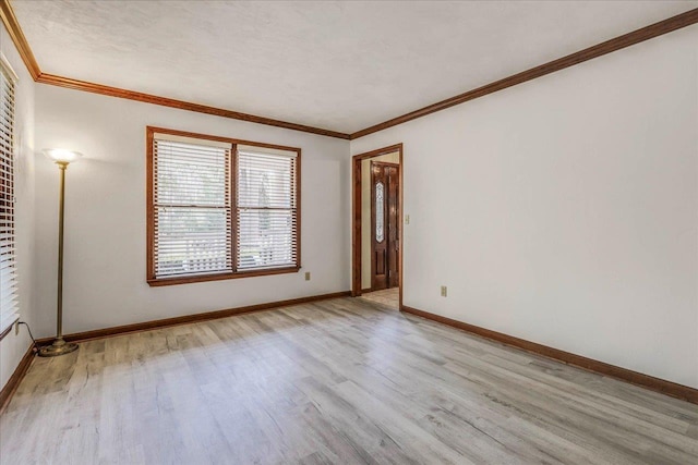 empty room featuring light wood-style floors, crown molding, and baseboards