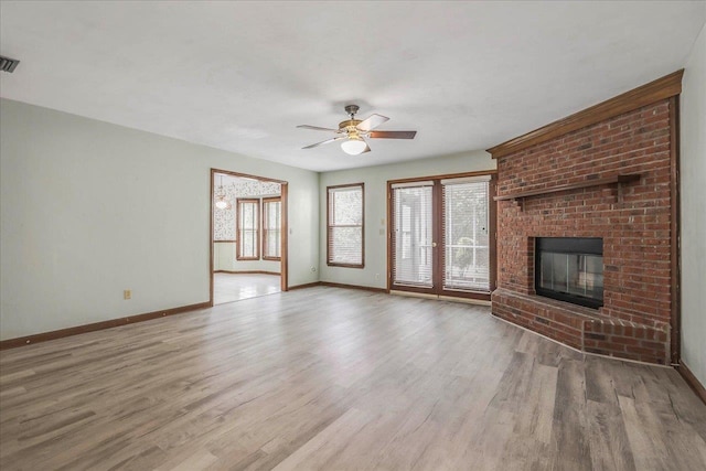 unfurnished living room featuring visible vents, a brick fireplace, ceiling fan, wood finished floors, and baseboards