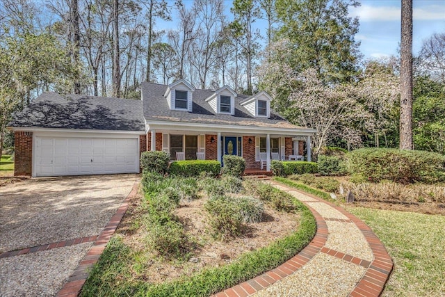 cape cod-style house featuring a garage, driveway, brick siding, and a porch