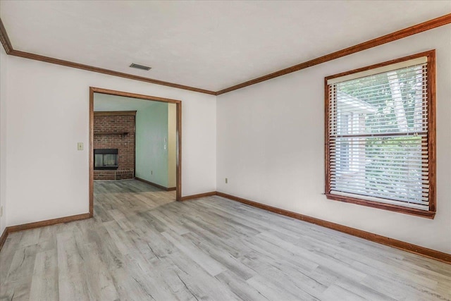 unfurnished room with baseboards, visible vents, ornamental molding, light wood-style floors, and a fireplace