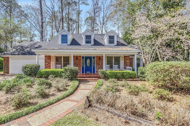 cape cod-style house featuring roof with shingles, brick siding, a porch, and an attached garage