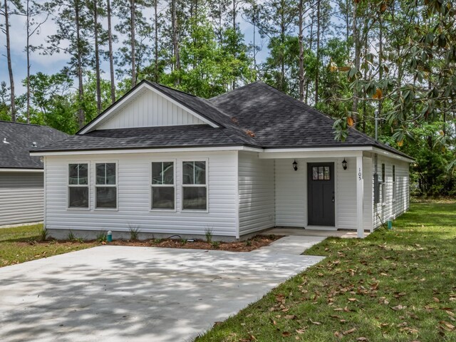 ranch-style home featuring a shingled roof and a front yard