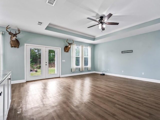 empty room featuring a raised ceiling, visible vents, crown molding, and dark wood-type flooring