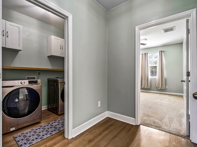 laundry area with cabinet space, visible vents, independent washer and dryer, and wood finished floors