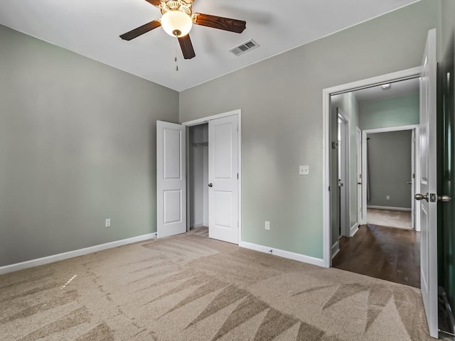 unfurnished bedroom with carpet flooring, a ceiling fan, visible vents, and baseboards