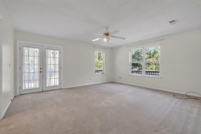 carpeted empty room with ceiling fan, french doors, and a textured ceiling