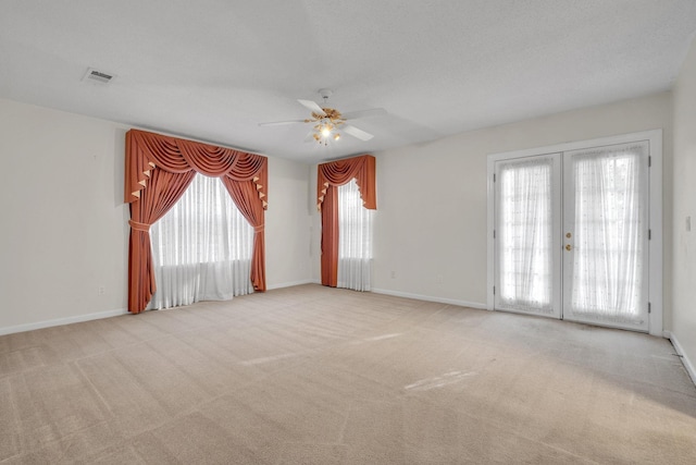 carpeted spare room featuring a textured ceiling, ceiling fan, and french doors