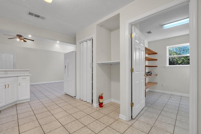 corridor featuring a textured ceiling and light tile patterned floors