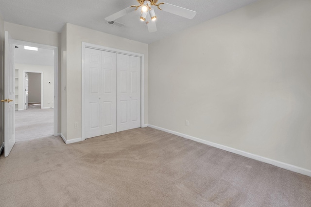 unfurnished bedroom featuring ceiling fan, a closet, and light carpet