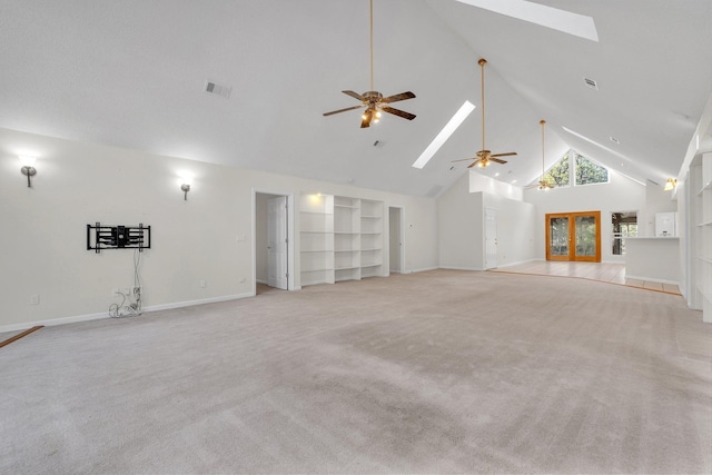 unfurnished living room with ceiling fan, light colored carpet, high vaulted ceiling, and a skylight