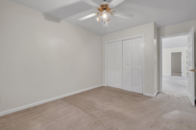 unfurnished bedroom featuring ceiling fan, a closet, and light carpet