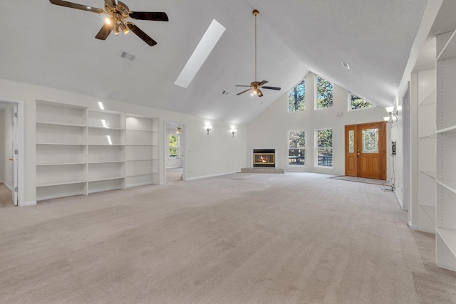 unfurnished living room with ceiling fan, light colored carpet, a high ceiling, and built in shelves