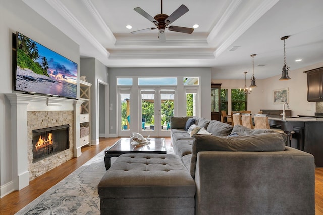 3260 Coneflower Dr, Tallahassee, FL 32311 - living area with a tray ceiling, a stone fireplace, wood finished floors, ceiling fan, and crown molding