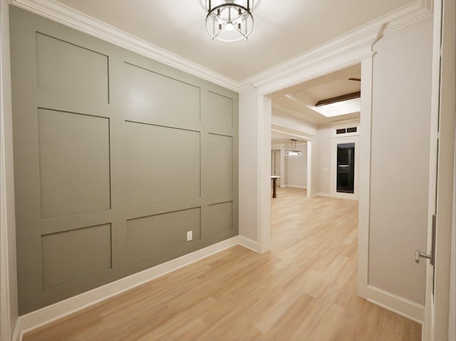 corridor featuring light wood-type flooring, crown molding, and a notable chandelier