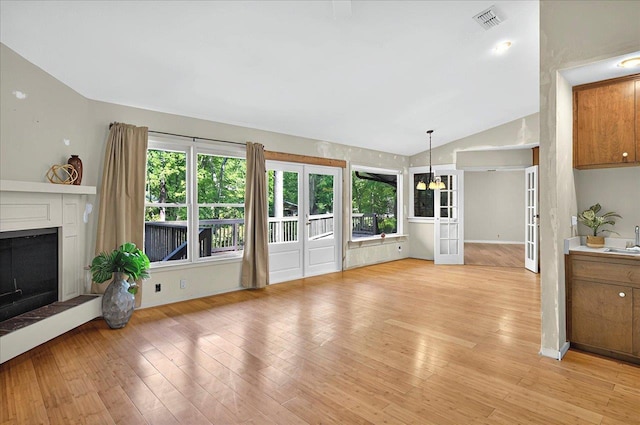 unfurnished living room featuring light wood-style flooring, a healthy amount of sunlight, a sink, and lofted ceiling