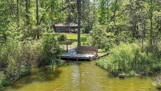 view of dock with a water view and a forest view