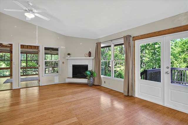 unfurnished living room with a fireplace with raised hearth, light wood-style flooring, vaulted ceiling, and a ceiling fan