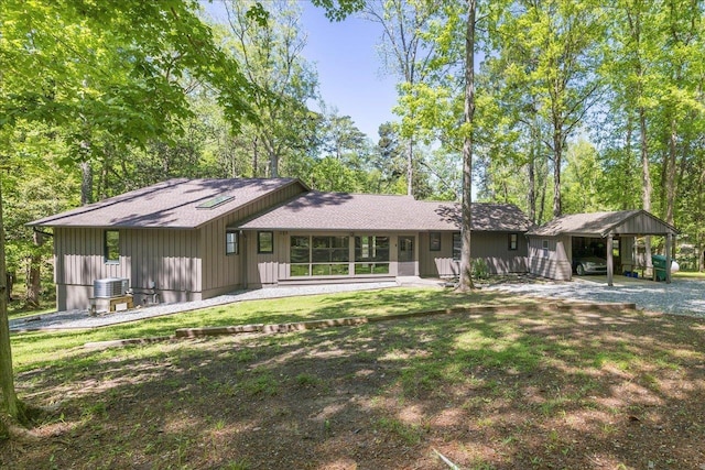 back of house featuring a yard, a shingled roof, and central AC unit