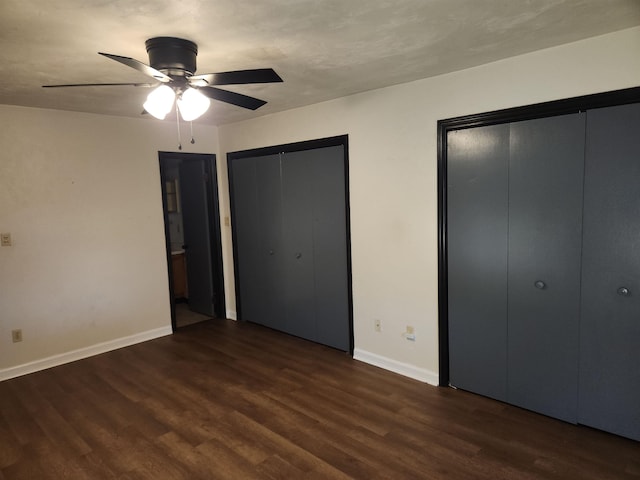 unfurnished bedroom with multiple closets, ceiling fan, and dark hardwood / wood-style flooring