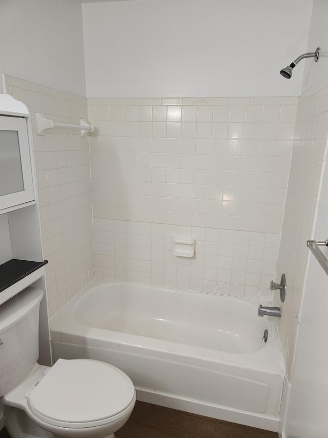 bathroom with hardwood / wood-style flooring, tiled shower / bath, and toilet