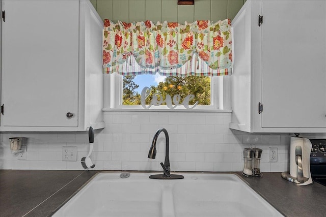 interior details with decorative backsplash, sink, and white cabinets