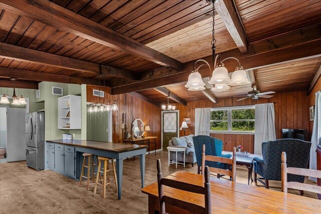 kitchen with beamed ceiling, stainless steel refrigerator, and wooden walls