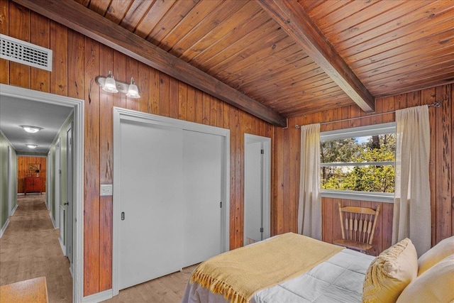 bedroom with wood walls, wood ceiling, beam ceiling, and a closet