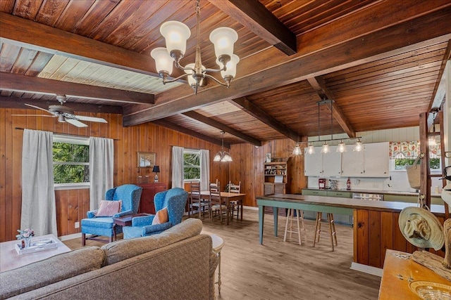 living room with ceiling fan with notable chandelier, wooden walls, light hardwood / wood-style flooring, wooden ceiling, and vaulted ceiling with beams