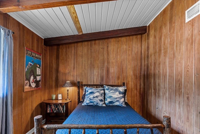 bedroom featuring beamed ceiling and wooden walls