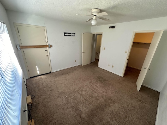 unfurnished bedroom with carpet flooring, a textured ceiling, ceiling fan, and a spacious closet