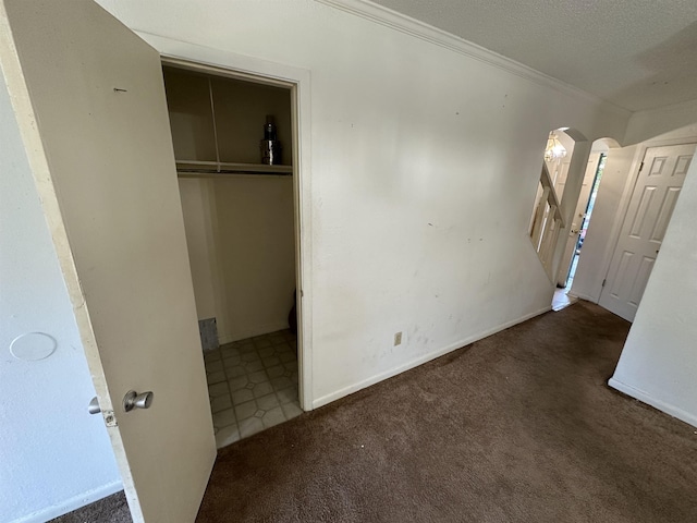 unfurnished bedroom with ornamental molding, dark carpet, and a closet