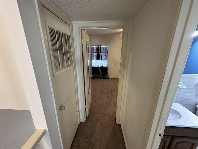 corridor featuring carpet flooring, a textured ceiling, and tile walls