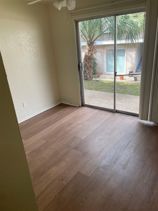 spare room with wood finished floors, a ceiling fan, and baseboards