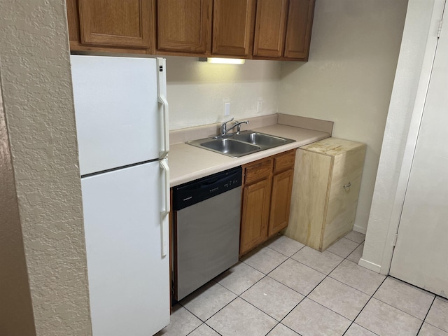kitchen featuring dishwasher, freestanding refrigerator, a sink, light countertops, and light tile patterned flooring