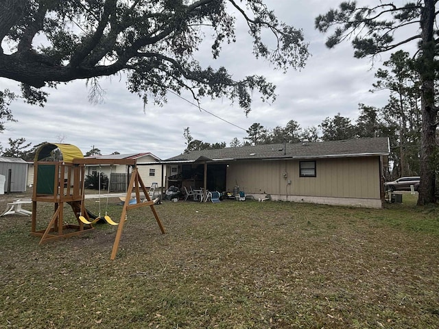 rear view of house featuring a playground and a lawn