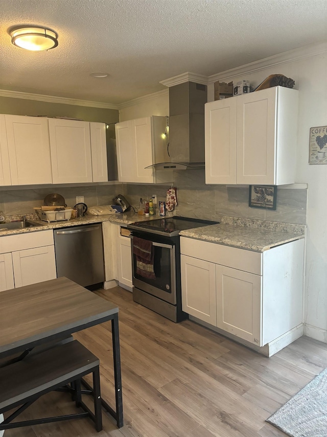 kitchen with wall chimney exhaust hood, white cabinetry, a textured ceiling, light wood-type flooring, and appliances with stainless steel finishes