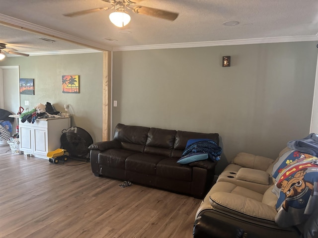 living room featuring crown molding, ceiling fan, wood-type flooring, and a textured ceiling