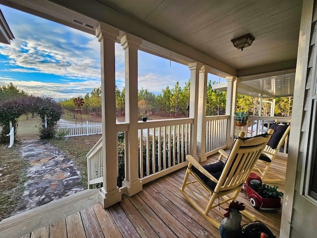 wooden terrace with a water view and covered porch