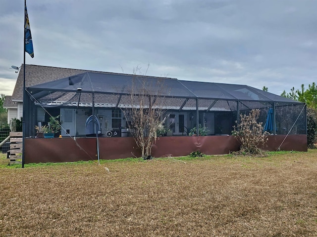 back of house featuring a lanai and a lawn