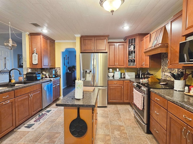 kitchen featuring premium range hood, a kitchen island, sink, appliances with stainless steel finishes, and ornamental molding