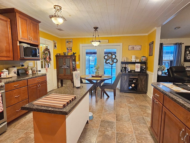 kitchen with pendant lighting, a center island, stove, crown molding, and french doors