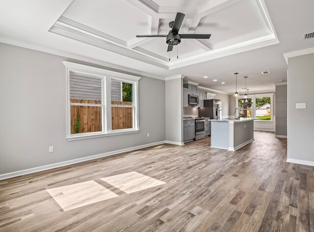 unfurnished living room with ceiling fan, sink, light hardwood / wood-style flooring, and ornamental molding