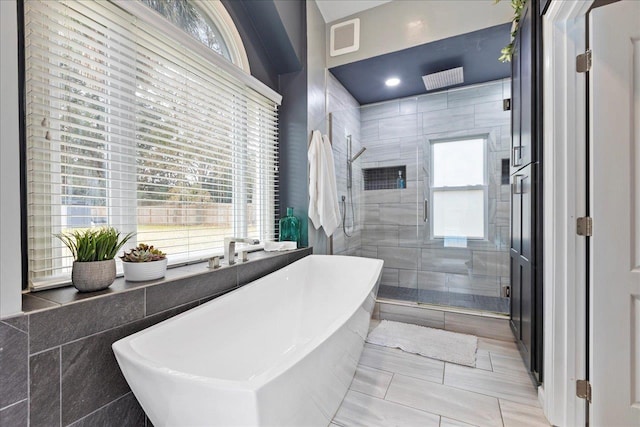 bathroom with plenty of natural light, shower with separate bathtub, and tile walls