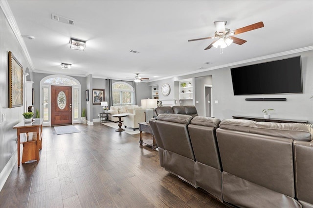 living room featuring ornamental molding, dark wood-type flooring, ceiling fan, and built in shelves