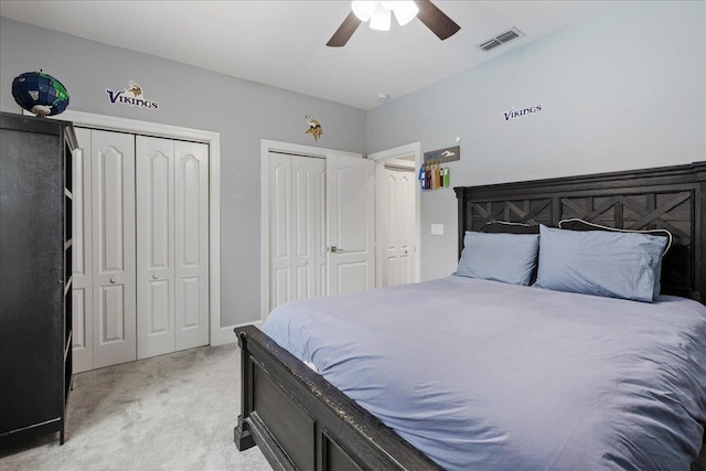 carpeted bedroom with ceiling fan and two closets