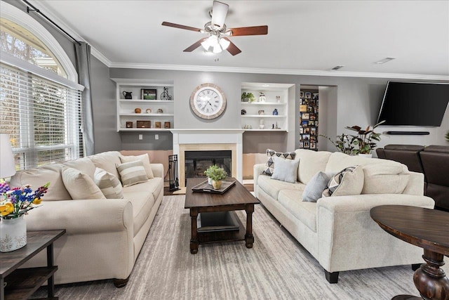 living room with ceiling fan, crown molding, and built in shelves