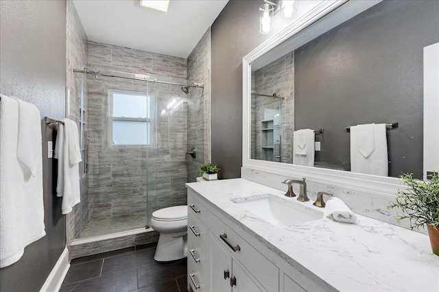 bathroom featuring vanity, toilet, and a shower with shower door