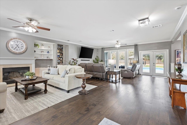 living room with a fireplace, crown molding, wood-type flooring, and french doors